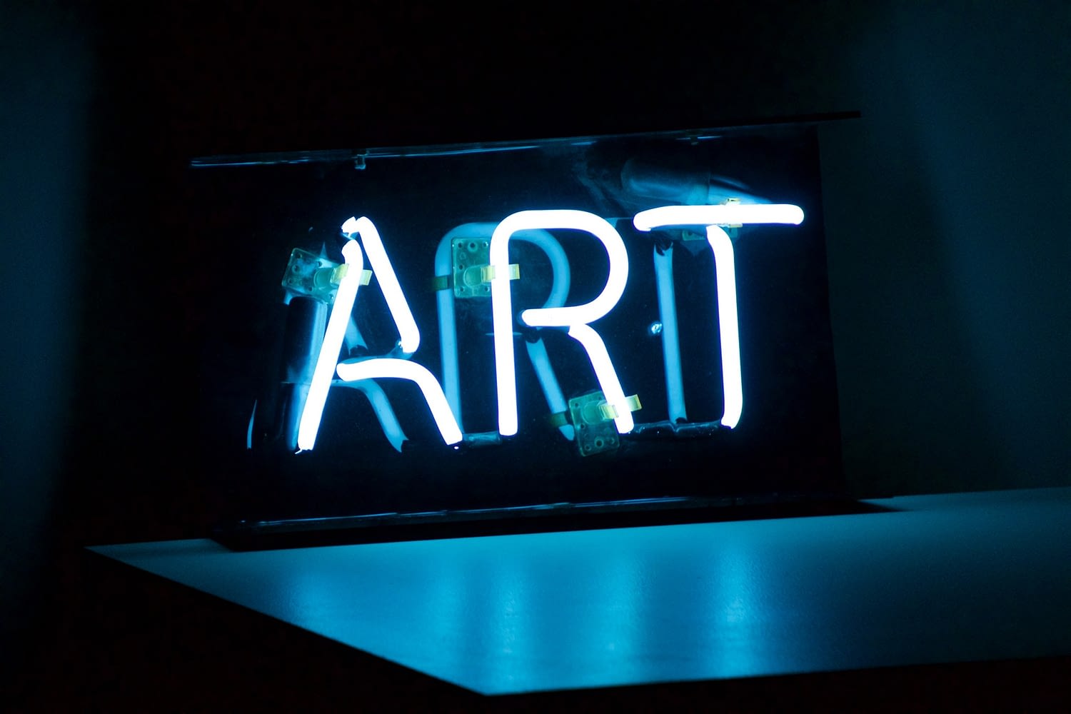 Neon sign spelling out the work ART in bright blue light